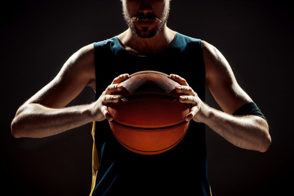 Silhouette view of a basketball player holding basket ball on black background